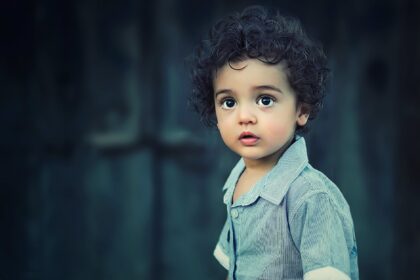 toddle wearing gray button collared shirt with curly hair