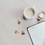 mug watch and planner book on brown wooden surface