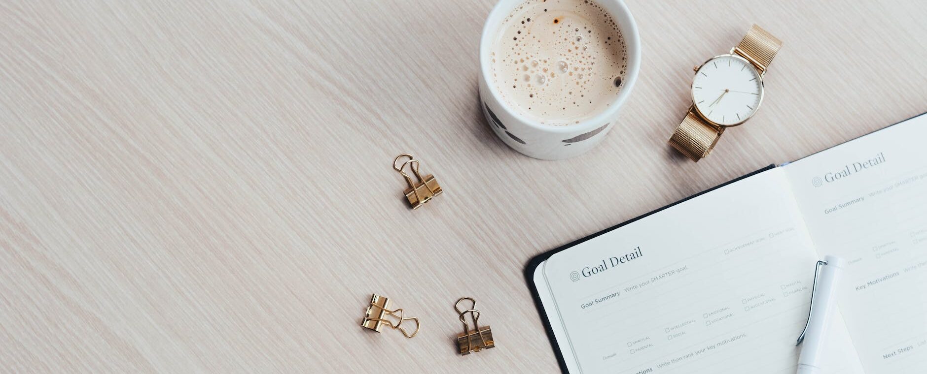 mug watch and planner book on brown wooden surface